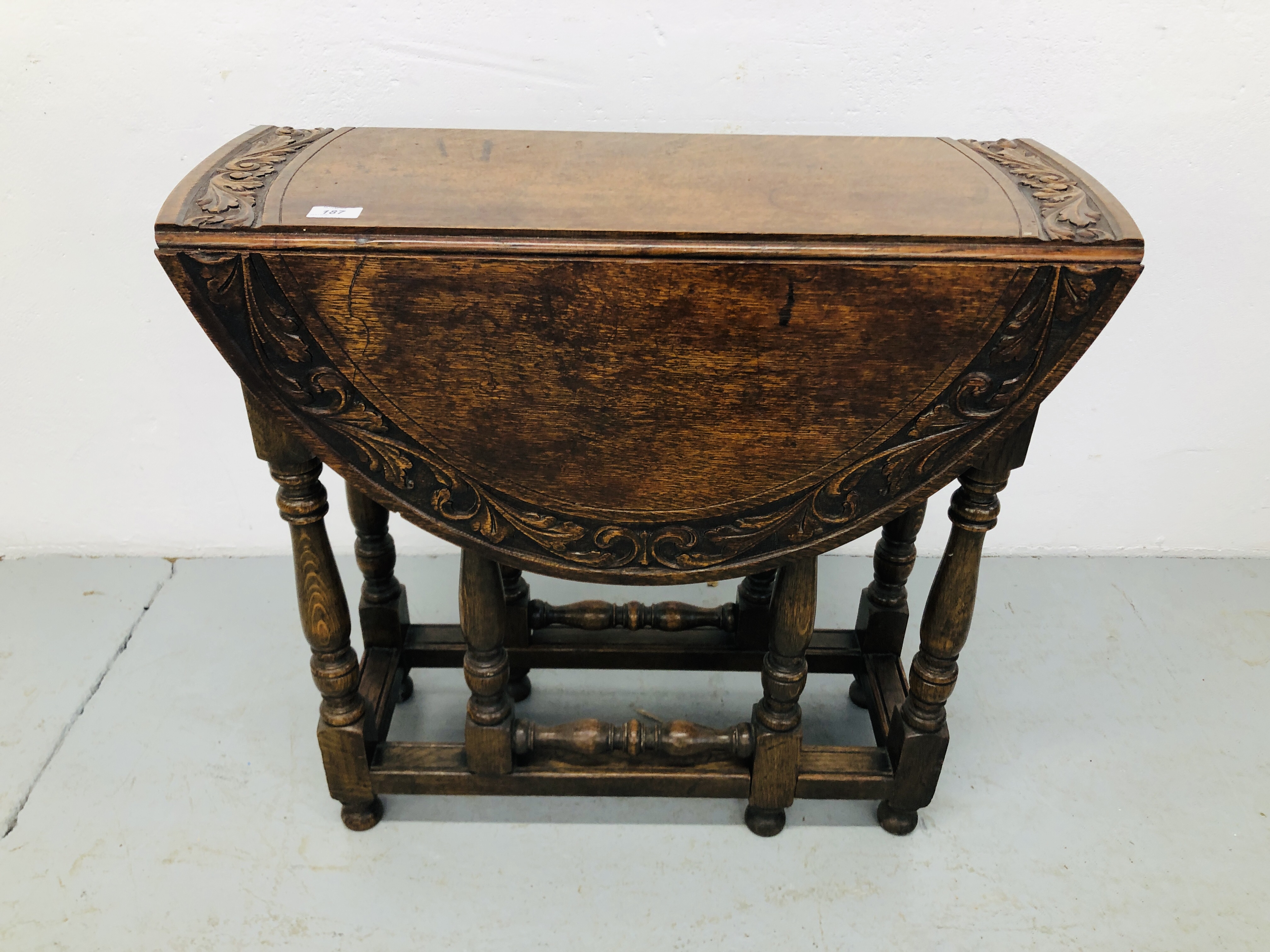 A REPRODUCTION SOLID OAK OVAL TOP GATELEG OCCASIONAL TABLE WITH CARVED DECORATION,