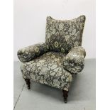 A VICTORIAN UPHOLSTERED ARMCHAIR ON TURNED MAHOGANY LEGS WITH BRASS CASTORS