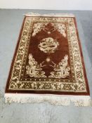 A CHINESE CREAM BROWN DECORATED CARPET ON ORANGE GROUND WITH DRAGON DESIGN. L 180CM. W 120CM.