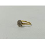 A NINE STONE DIAMOND FLOWER HEAD RING (RUBBED HALL MARKS)