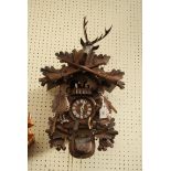 An early 20th century Black Forest carved wall clock, with painted rotating peasant figures