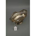 A fruit bowl, oval with scroll pierced decoration to undulating borders, spreading oval foot,