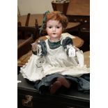 C. M. Bergman of Germany, a bisque porcelain headed doll with sleeping eyes, real hair and dress
