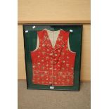 An 18th century style West Country cloth waistcoat, with hand embroidered flowers on its red ground,