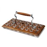 A SMALL SHOT-GLASS DRINKS SERVING TRAY, 32 miniature nip glasses set in an oak base with globe