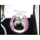 A silver horseshoe/horse head brooch set with rubi