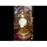A decorative gilt mantel clock under glass dome -