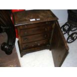 A four drawer miniature chest with panelled door
