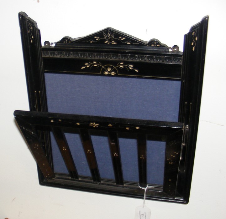 An ebonized hanging paper rack