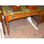 An antique desk with green leather top and three d