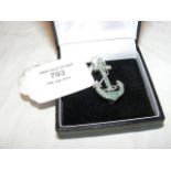 A solid silver anchor set with emeralds