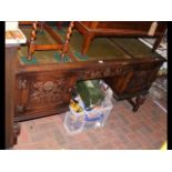 A carved oak writing desk with inset green leather