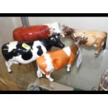 A Beswick cow ornament, together with three others