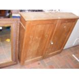 A pine wall cabinet enclosed by a pair of panelled