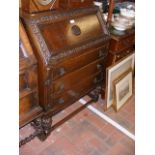 A 1920's carved oak bureau with three drawers unde