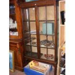 A mahogany display cabinet enclosed by a pair of g