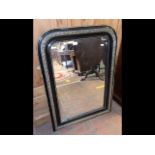 An antique overmantel mirror in ebony and gilt fra