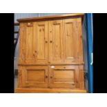 A pine cupboard enclosed by a pair of panelled doo