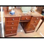 An antique leather top desk with nine drawers to t