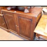 A mahogany two door panelled cupboard with slides