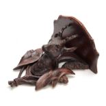 A CARVED BLACK FOREST SHAPED HANGING BRACKET with carved deer head supported flanked by leaf work
