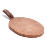 A ROBERT MOUSEMAN THOMPSON OAK CHEESEBOARD of oval form with curved handle carved with a mouse