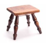 A 19TH CENTURY ELM STOOL with thick-cut chamfered top and four ring-turned leg supports 22cm wide