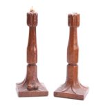 A PAIR OF EARLY ROBERT MOUSEMAN THOMPSON OAK CANDLESTICKS with leaf carved sconces and facetted