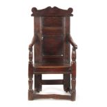 A 17TH CENTURY JOINED OAK WAINSCOT CHAIR with a shaped top rail above a panelled back with swept