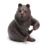 A 19TH CENTURY SWISS CARVED BLACK FOREST SEATED BEAR INKWELL with hinged lid and arm outstretched