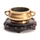 AN EARLY CHINESE CAST BRASS CENSER of squat form with side handles, having a crest underneath -