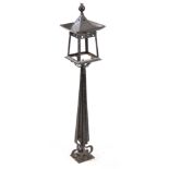 AN ARTS AND CRAFT PAINTED METAL NEWEL POST LANTERN of square stylised form with tapering supports