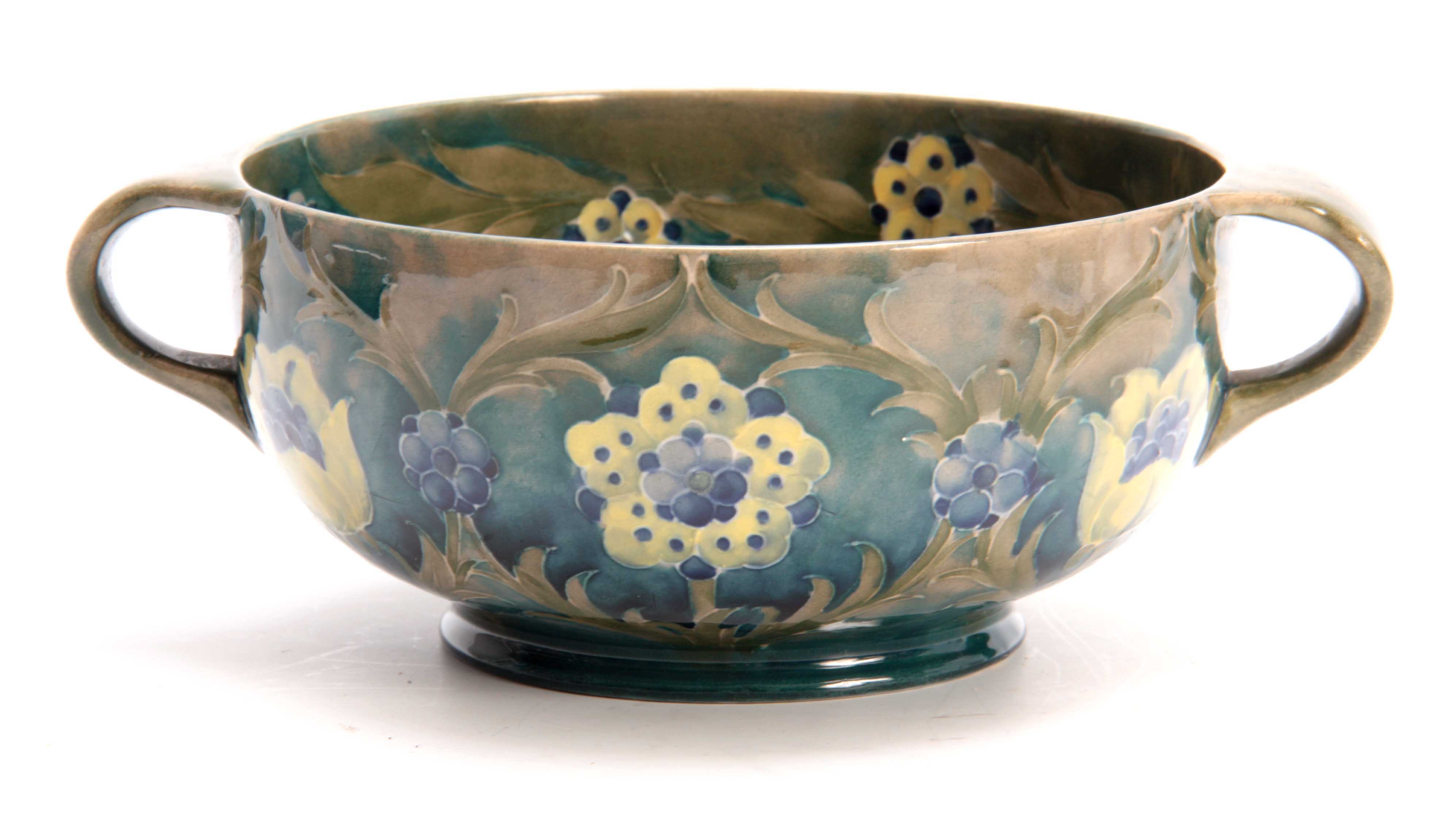 A WILLIAM MOORCROFT BURSLEM FOOTED TWO-HANDLED BOWL with flowerhead and leaf spray decoration on a