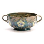 A WILLIAM MOORCROFT BURSLEM FOOTED TWO-HANDLED BOWL with flowerhead and leaf spray decoration on a