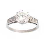 A FINE 18CT WHITE GOLD BRILLIANT CUT SOLITAIRE DIAMOND RING claw set with small three stone tapering