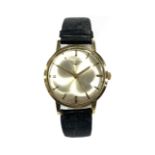 A GENTLEMANS 9ct GOLD LONGINES WRIST WATCH on a black leather strap, having a silvered dial with
