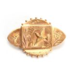 A YELLOW GOLD BROOCH with panelled centre depicting a raised bird and foliage within a shaped