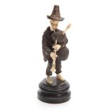 A BLACK FOREST BONE AND CARVED WOOD STANDING MALE FIGURE OF A TYROLEAN MUSICIAN on circular base