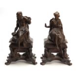 A PAIR OF 19TH CENTURY CAST BRASS CHENET / FIREDOGS depicting a seated couple warming there hands