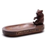 A LATE 19TH CENTURY SWISS BLACK FOREST BEAR DESK TIDY with a seated bear on an oval dished base with