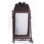 A QUEEN ANNE WALNUT TOILET MIRROR WITH LEAF AND SHELL CARVED CREST, moulded frame and turned