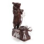 AN EARLY 20th CENTURY CARVED BLACK FOREST MUSICAL DECANTER STAND modelled as a standing bear