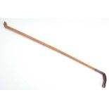 AN EARLY 20th CENTURY RHINO HORN RIDING CROP with carved horse's foot handle, knotched cane and