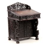 A 19TH CENTURY CARVED HARDWOOD DAVENPORT with carved figural gallery above an angled leather writing