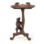 A LATE 19TH CENTURY SWISS CARVED BLACK FOREST SMOKERS TABLE with leaf carved top having two bear