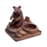 A LATE 19TH CENTURY SWISS BLACK FOREST CARVED BEAR PIPE STAND depicting a seated bear on a