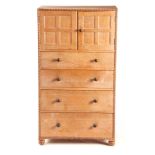 HEAL & SON, LONDON A COTSWOLD SCHOOL STYLE OAK CABINET ON CHEST of dovetailed construction with
