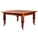 A 19TH CENTURY OAK EXTENDING DINING TABLE with three extra leaves; standing on leaf carved turned