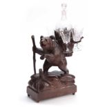 A LATE 19TH CENTURY SWISS CARVED BLACK FOREST BEAR MUSICAL DECANTER SET modelled as a bear