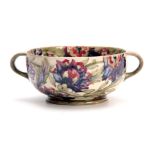 A WILLIAM MOORCROFT BURSLEM FOOTED TWO-HANDLED BOWL with colourful tube lined flowerhead and leaf